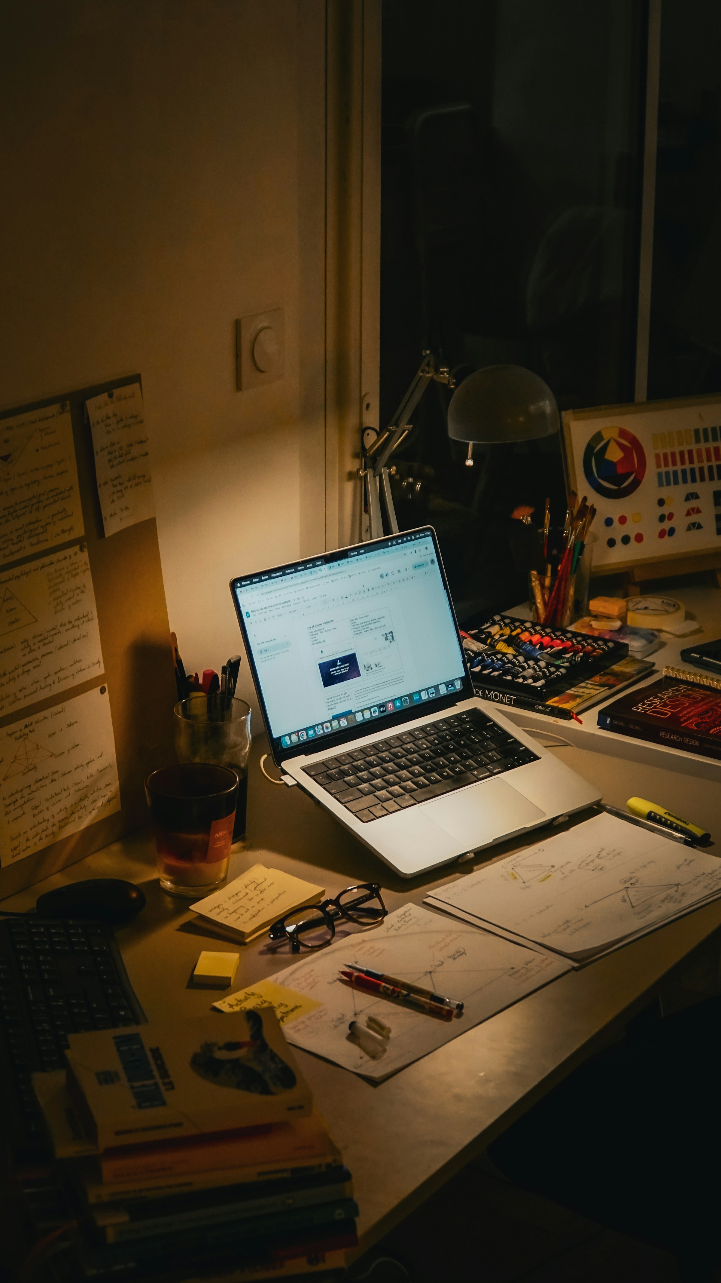 Busy desk with laptop, books, notes and work materials